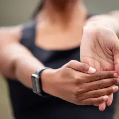 Une femme étire son poignet, peut-être pour soulager une douleur poignet externe après un effort.