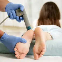 Thérapie par ondes de choc pour l'aponévrosite plantaire. Un professionnel applique le traitement sur le pied d'une patiente.