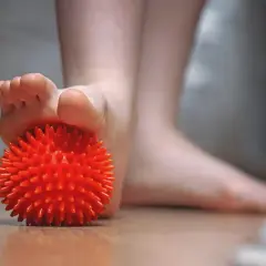 Un pied utilise une balle rouge texturée pour soulager une tendinite sous le pied.