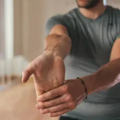 Un homme s'étire le poignet, soulageant une douleur avant-bras extérieur.