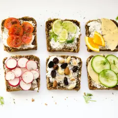 Six tartines variées : tomates, radis, agrumes, fromage, fruits secs et concombre. Un menu type femme 50 ans, sain et coloré.