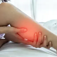 Une personne se tient la jambe, le mollet dur et gonflé, avec une zone rouge indiquant la douleur.