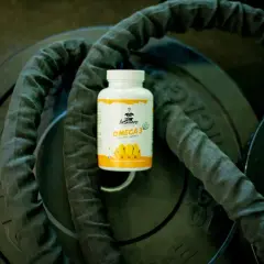 Bouteille d'oméga 3 sur des poids de musculation, idéale pour le bien-être, matin ou soir.