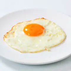 Un œuf au plat, bien cuit, sur une assiette blanche. Le jaune est bien rond et brillant, parfait pour un petit-déjeuner nourrissant.
