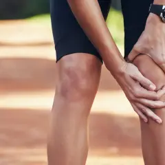 Une athlète se tient le genou, peut-être une douleur au ligament croisé du pied.