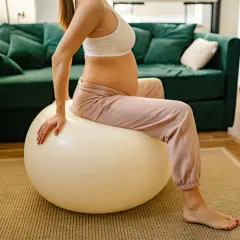 Femme enceinte assise sur un ballon de gym pour un exercice d'ouverture du col.
