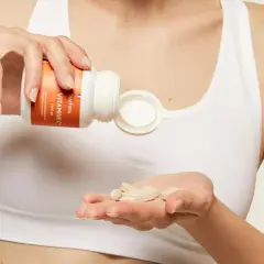 Une main verse des comprimés de vitamine C dans l'autre main, pour une cure de vitamine essentielle.