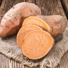 Patates douces entières et tranchées sur une toile de jute. Un aliment sain, faible en calories, parfait pour une alimentation équilibrée.