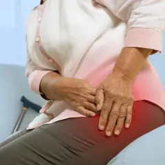 Une personne âgée ressent une douleur à la hanche, peut-être due à une ancienne blessure de course à pied. Une canne est visible à proximité.