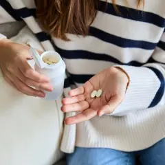 Une femme tient des comprimés dans sa main, peut-être pour lutter contre la fatigue. Le collagène est une option.