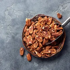 Un panier rempli de noix de pécan, une cuillère métallique en extrait. Savourez les noix de pécan, un concentré de bienfaits pour la santé.