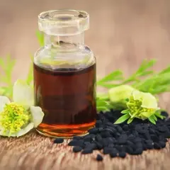 Flacon d'huile de nigelle, graines noires et fleurs. Un remède naturel pour la fonte musculaire.