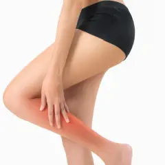 Une femme se tient la jambe droite, une zone rouge vif indiquant une douleur au mollet droit.