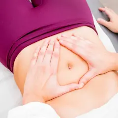 Mains douces explorant le ventre, cherchant à soulager une douleur bas ventre.
