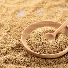 Un bol en bois rempli de graines de sésame, avec une cuillère en bois. Les graines de sésame bienfait sont une source de nutriments.