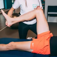 Un kinésithérapeute aide un patient à soulager sa douleur musculaire au genou lors d'une séance de rééducation.