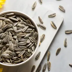 Un bol rempli de graines de tournesol, rappelant les nombreux bienfaits de ce superaliment. Quelques graines sont éparpillées autour.