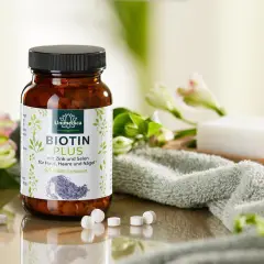 Flacon de Biotin Plus, une réponse à quelle vitamine pour les ongles, avec des fleurs et une serviette.
