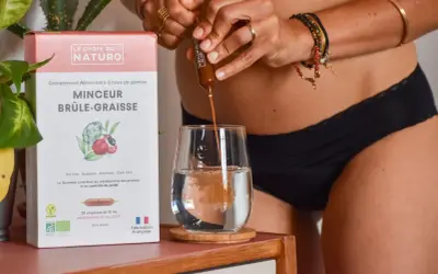 Une personne verse un ampoule d'un brule graisse naturel dans un verre d'eau. La boîte indique "Minceur Brûle-Graisse".