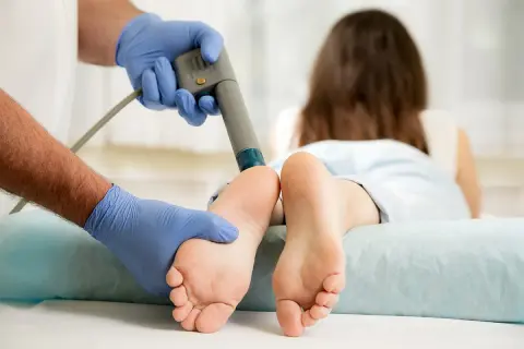 Thérapie par ondes de choc pour l'aponévrosite plantaire. Un professionnel applique le traitement sur le pied d'une patiente.