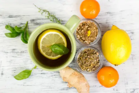 Tasse de thé au citron et herbes, gingembre, clémentines. Un remède de grand-mère pour le rhume de cerveau.