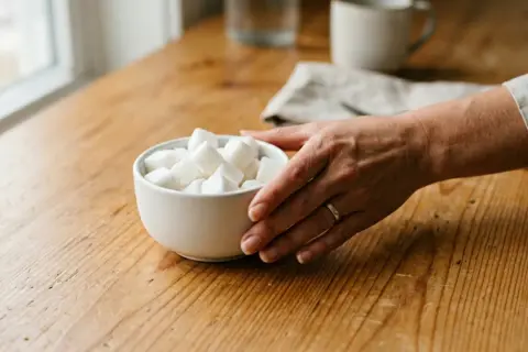 Main tenant une coupe de sucre, une main se prépare à comment se sevrer du sucre.