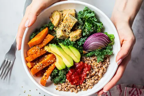 Un bol coloré avec patates douces, avocat, tofu, chou kale et oignon rouge. Une délicieuse alimentation anti cholestérol.