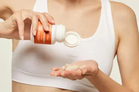 Une main verse des comprimés de vitamine C dans l'autre main, pour une cure de vitamine essentielle.