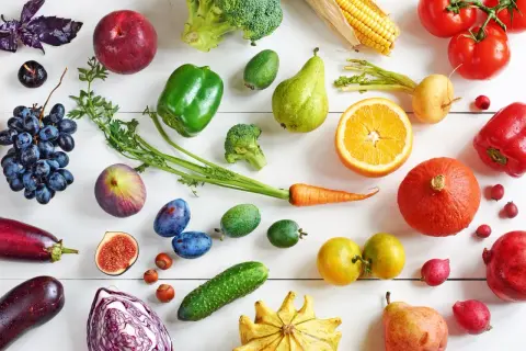 Un assortiment coloré de fruits et légumes frais, incluant des tomates, des poivrons, des carottes, des oranges, des poires, des raisins, des figues, des prunes, des courges, des brocolis, des aubergines, des choux rouges, des concombres et des maïs. C...