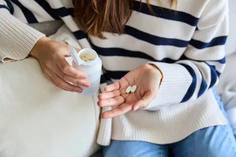 Une femme tient des comprimés dans sa main, peut-être pour lutter contre la fatigue. Le collagène est une option.