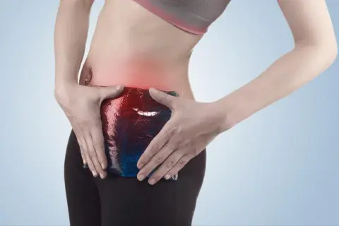 Femme appliquant une poche de glace sur sa zone douloureuse, symptomatique d'une pubalgie sans sport.