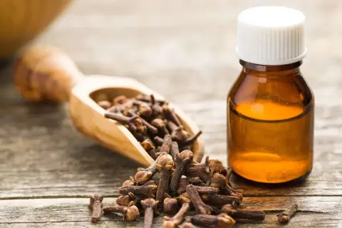 Clous de girofle et une fiole d'huile essentielle, suggérant un traitement naturel pour l'intoxication alimentaire.