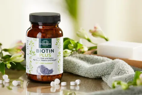 Flacon de Biotin Plus, une réponse à quelle vitamine pour les ongles, avec des fleurs et une serviette.