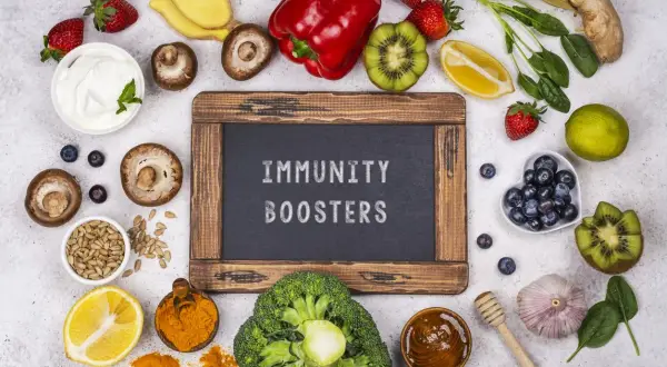 Assortiment d'aliments colorés : fraises, kiwis, brocolis, citron, curcuma, ail, gingembre, myrtilles, champignons, poivron rouge, épinards, graines de tournesol, yaourt. Ces aliments sont excellents pour le système immunitaire.