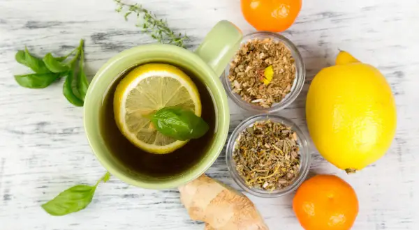 Tasse de thé au citron et herbes, gingembre, clémentines. Un remède de grand-mère pour le rhume de cerveau.