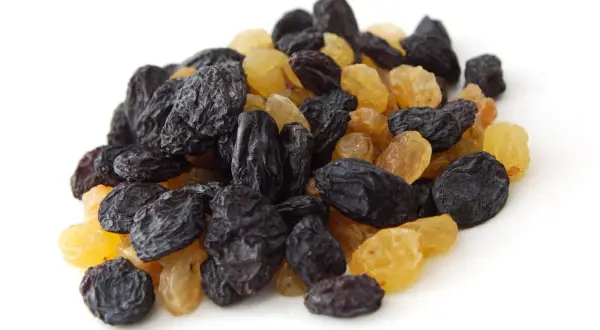 Un tas de raisins secs noirs et dorés, rappelant les méfaits du raisin sec sur la santé si consommés en excès.