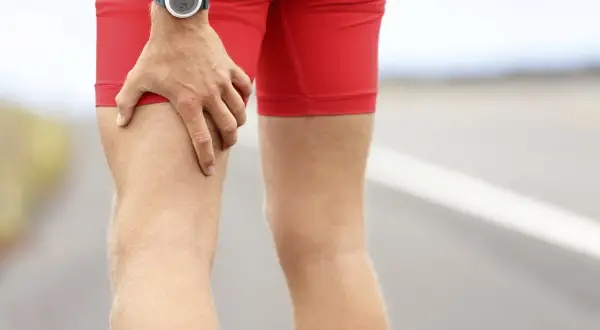 Un coureur s'arrête, une main sur sa cuisse, peut-être une douleur pointe derrière la cuisse.