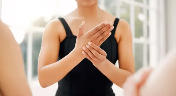 Une danseuse se tient la main droite, le petit doigt semble lui causer une douleur.
