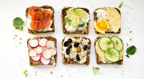 Six tartines variées : tomates, radis, agrumes, fromage, fruits secs et concombre. Un menu type femme 50 ans, sain et coloré.