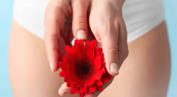 Mains tenant une fleur rouge, évoquant le déséquilibre flore intime symptômes.