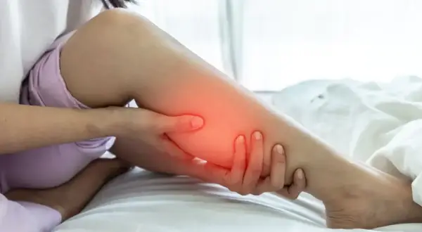 Une personne se tient la jambe, le mollet dur et gonflé, avec une zone rouge indiquant la douleur.