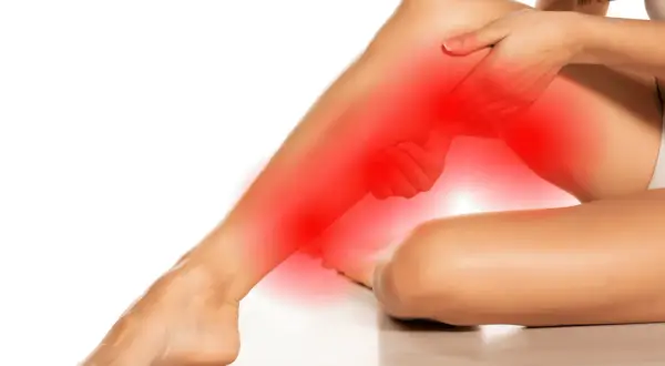 Femme se tenant la jambe, zone rouge indiquant la douleur. Des conseils pour comment soulager une sciatique.