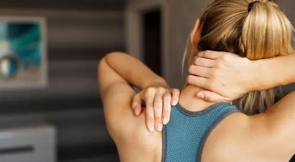 Femme se tenant le cou, souffrant de muscles du cou douloureux après une longue journée.