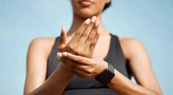 Une femme masse ses mains, peut-être à cause d'une douleur phalange doigt après un entraînement.