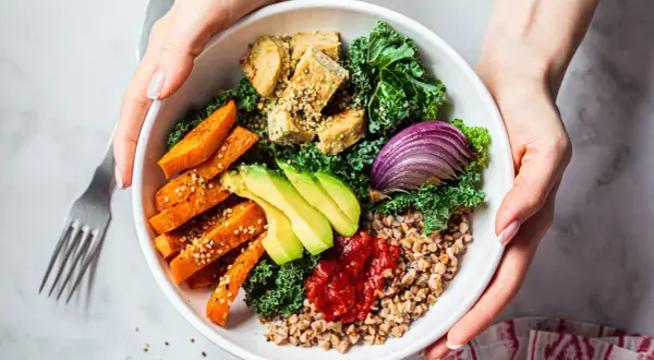 Un bol coloré avec patates douces, avocat, tofu, chou kale et oignon rouge. Une délicieuse alimentation anti cholestérol.