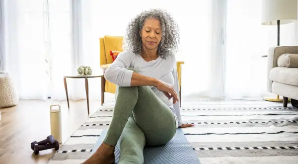Femme pratiquant des étirements pour soulager son arthrose lombaire, une marche douce peut aussi aider.