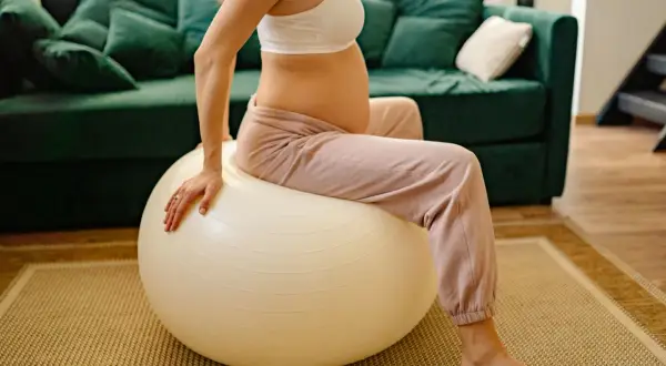 Femme enceinte assise sur un ballon de gym pour un exercice d'ouverture du col.