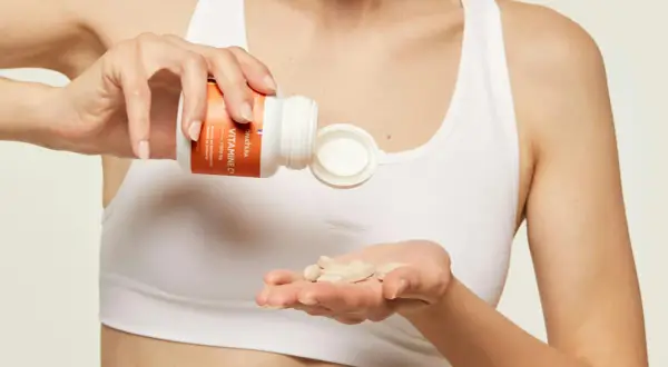 Une main verse des comprimés de vitamine C dans l'autre main, pour une cure de vitamine essentielle.
