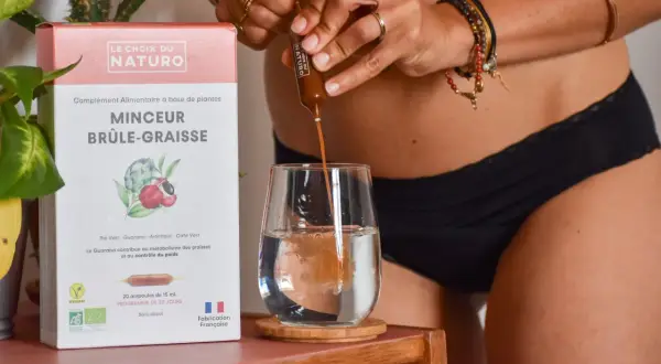 Une personne verse un ampoule d'un brule graisse naturel dans un verre d'eau. La boîte indique "Minceur Brûle-Graisse".