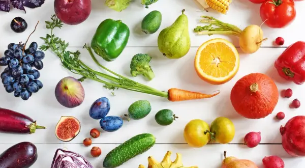 Un assortiment coloré de fruits et légumes frais, incluant des tomates, des poivrons, des carottes, des oranges, des poires, des raisins, des figues, des prunes, des courges, des brocolis, des aubergines, des choux rouges, des concombres et des maïs. C...